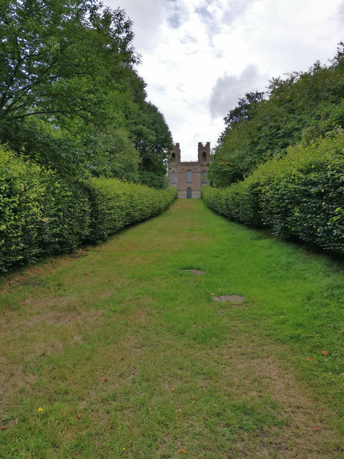 Building after hedge lined path